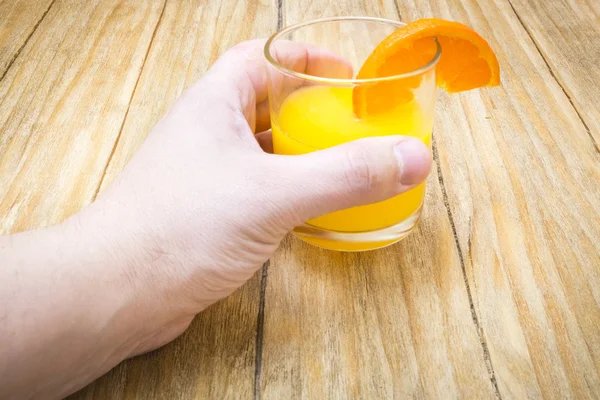 Mehrere reife Zitrusfrüchte und ein Glas Saft auf einem Holztisch — Stockfoto