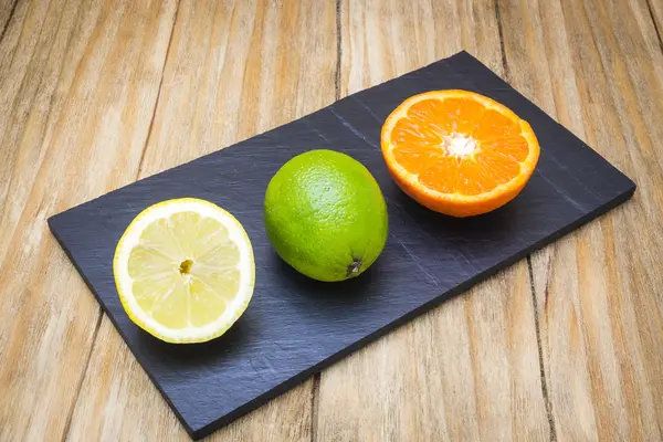 Mehrere reife Zitrusfrüchte auf einem Holztisch auf einer Tafel — Stockfoto