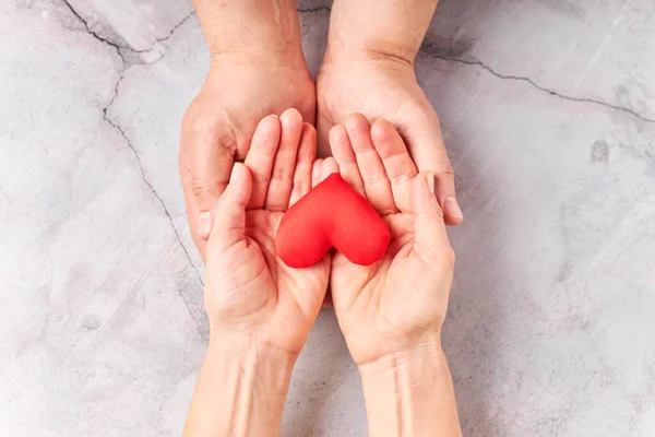 Hands holding a red heart, health care, donate. world heart day, world health day