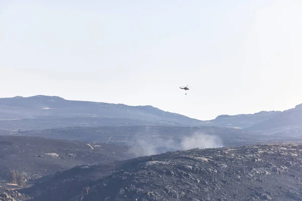 Helicopters over a landscape burned by a forest fire, finishing putting it out. Fire concept