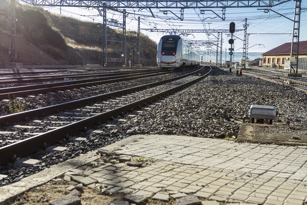 De närmar tåg på spåren till station av staden — Stockfoto