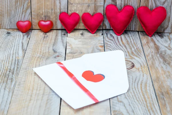 Több piros szív, egy fából készült háttér és a szív, a borítékba, Valentin-nap — Stock Fotó