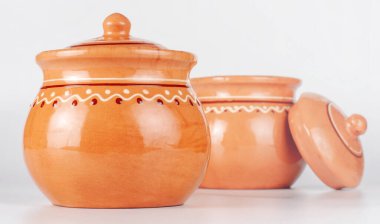 İki seramik, kahverengi kaplanmış tencere beyaz arka planda sıralanmış..