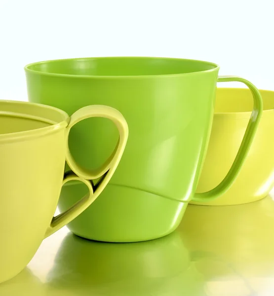 Three plastic mugs yellow and green Stock Photo
