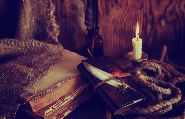 复古对象羽毛和皮革书与蜡烛发出的光 — 图库照片