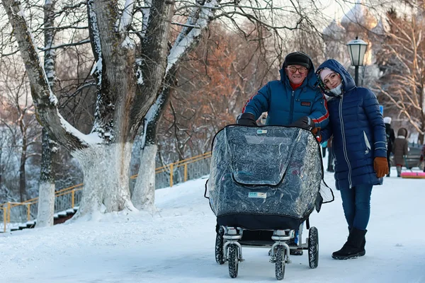 Vieux homme et femme marchent avec une poussette en hiver — Photo