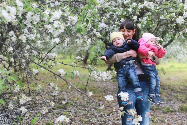 Mamma con gemelli in plaid all'aperto nel giardino delle mele — Foto Stock