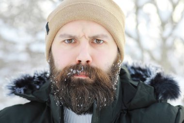 Kış ormanlarında sakallı adam. Çekici, mutlu, sakallı genç bir adam parkta yürüyor..