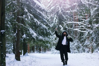 Kış ormanlarında sakallı adam. Çekici, mutlu, sakallı genç bir adam parkta yürüyor..