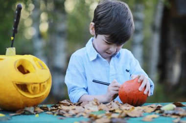 Sonbahar gelenekleri ve Cadılar Bayramı hazırlıkları. Doğada bir ev, masada balkabağından yapılmış bir lamba kesilir..