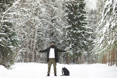 Kış ormanlarında sakallı adam. Çekici, mutlu, sakallı genç bir adam parkta yürüyor..