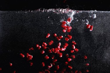 Olgun tatlı nar tohumlarına su damlaları düşer. Metnin için kopyalama alanı olan taze nar arkaplanı. Vejetaryen ve vejetaryen kavramı.