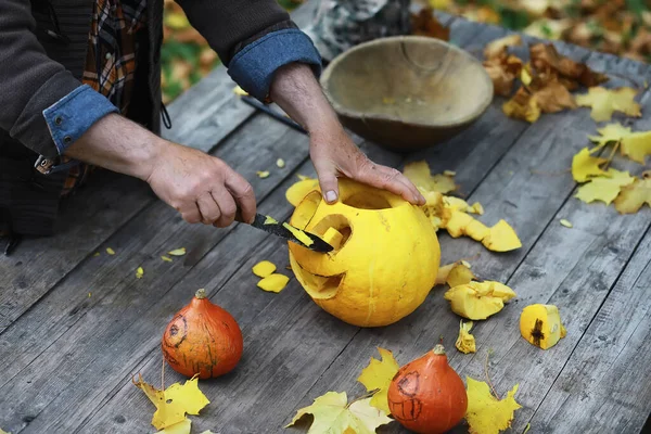 Autumn traditions and preparations for the holiday Halloween. A house in nature, a lamp made of pumpkins is cut out at the table.