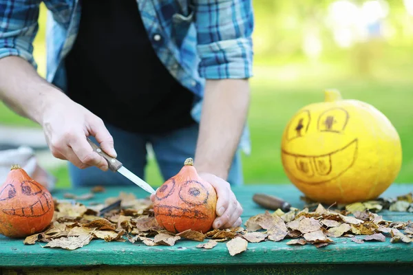 Autumn traditions and preparations for the holiday Halloween. A house in nature, a lamp made of pumpkins is cut out at the table.