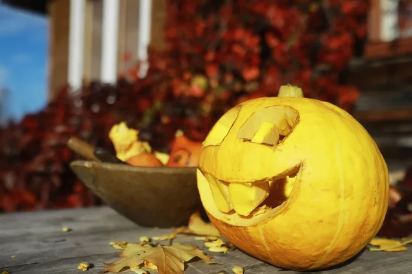 Autumn traditions and preparations for the holiday Halloween. A house in nature, a lamp made of pumpkins is cut out at the table.