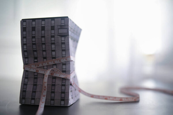 Концепция финансовой зависимости от заемных средств. Ипотечные долги. Дом обмотают скотчем с табличкой доллара.