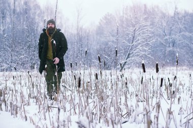 Kış ormanlarında sakallı adam. Çekici, mutlu, sakallı genç bir adam parkta yürüyor..