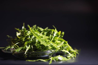 Taze roka kevgirle yapılır. Siyah arka plan. Yeşil yapraklı ve sebzeli yeşil vejetaryen salatası.