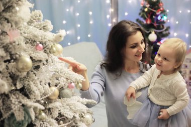 Yeni yıl arifesi. Ev tatil için dekore edildi. Zarif giyimli Noel ağacı, bir çelenk ve hediyeli bir aile ve sürpriz..