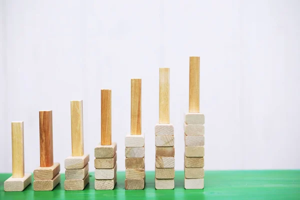 Stick wood block standing on stacked square wood blocks, abstract background concept of winning, success, challenge, step to top position.