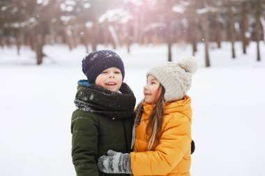 Mutlu bir aile kışın dışarıda karda oynar ve güler. Şehir parkı kış günü.