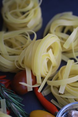 Baharatlı ve sebzeli makarna. Siyah taş üzerinde yemek pişirmek için sebzeli erişte..