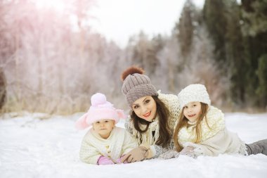 Mutlu bir aile kışın dışarıda karda oynar ve güler. Şehir parkı kış günü