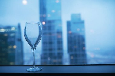 Pencere kenarında uzun bir binanın camının yanında kokteyl bardakları.