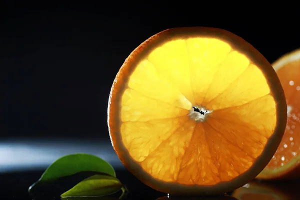 Composition with orange and grapefruit slices on a black background. A slice of orange on a black background with water drops. Juicy orange on a table.