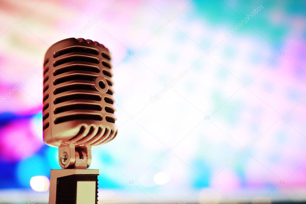 Retro style microphone on background with backlight. Vintage silver Microphone for sound, music, karaoke. Speech broadcast equipment. Live pop, rock musical performance. Selective focu