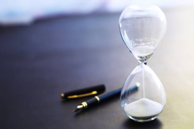 Kum saati ampulleri arasında koşan ve bir geri sayım bitiş tarihine kadar geçen zamanı ölçen, fotokopi alanı olan karanlık bir zemin arka planında..