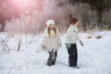 Mutlu bir aile kışın dışarıda karda oynar ve güler. Şehir parkı kış günü