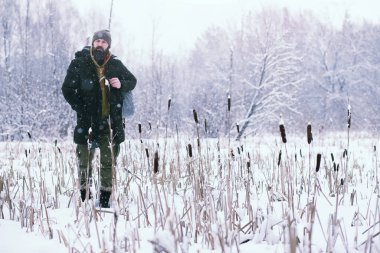 Kış ormanlarında sakallı adam. Çekici, mutlu, sakallı genç bir adam parkta yürüyor..