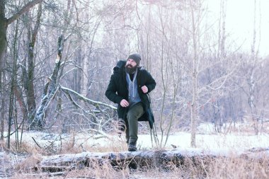 Kış ormanlarında sakallı adam. Çekici, mutlu, sakallı genç bir adam parkta yürüyor..