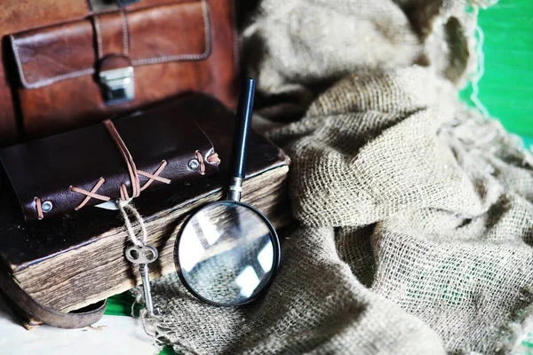 Old leather bag with a magnifying glass on a brown traveler wooden table background copy space.