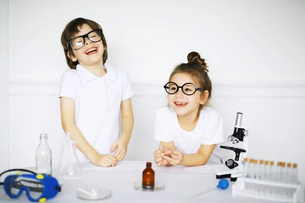 在化学课上两个可爱的孩子在白色背景上进行了分离实验 — 图库照片