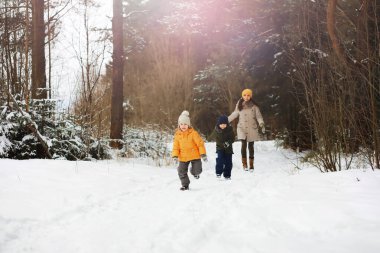 Mutlu bir aile kışın dışarıda karda oynar ve güler. Şehir parkı kış günü.