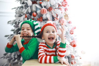 Noel Baba 'nın yardımcıları. Noel' de Noel için dekore edilmiş bir odada elf kostümleri giymiş şirin çocuklar. Mucizeler zamanı. Noel Baba 'dan hediyeler