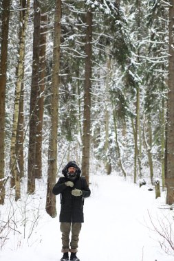 Kış ormanlarında sakallı adam. Çekici, mutlu, sakallı genç bir adam parkta yürüyor..