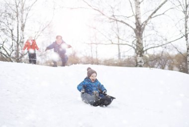 Kışın parktaki çocuklar. Çocuklar parkta karla oynarlar. Kardan adam heykeli yapıp tepelerden aşağı kayıyorlar..