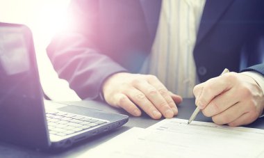 Müdür ofisteki bir dizüstü bilgisayarda çalışıyor. İşadamı çevrimiçi işlem yapıyor. Değiş tokuş internet üzerinden yapılıyor..