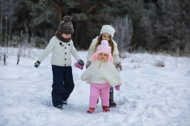 Mutlu bir aile kışın dışarıda karda oynar ve güler. Şehir parkı kış günü