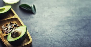 Avokado yemek tarifleri. Tahta kesme tahtasında servis edilen olgun yeşil avokado..