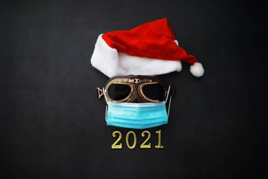 Noel Baba şapkası, gözlük ve kırmızı arka planda yüz maskesi olan bir burun. Noel ya da yeni yıl kutlaması konsepti. Koruyucu yüz maskesi ve dekorasyondan yapılmış Noel geyikleri. Sağlık hizmeti kavramı