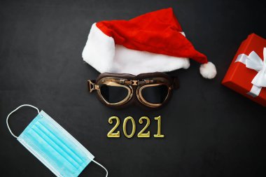 Noel Baba şapkası, gözlük ve kırmızı arka planda yüz maskesi olan bir burun. Noel ya da yeni yıl kutlaması konsepti. Koruyucu yüz maskesi ve dekorasyondan yapılmış Noel geyikleri. Sağlık hizmeti kavramı