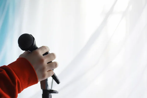 Stand with a microphone. Man holds hands a microphone on tripod. Performance of the artist with a microphone. Scene with a microphone.
