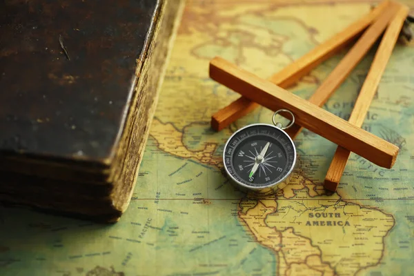 Travel and adventure search concept. Vintage aged map with shabby book and compass. Shabby book and compass on the table.