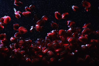 Olgun tatlı nar tohumlarına su damlaları düşer. Metnin için kopyalama alanı olan taze nar arkaplanı. Vejetaryen ve vejetaryen kavramı.