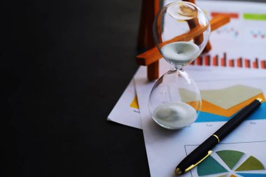 Kum saati ampulleri arasında koşan ve bir geri sayım bitiş tarihine kadar geçen zamanı ölçen, fotokopi alanı olan karanlık bir zemin arka planında..