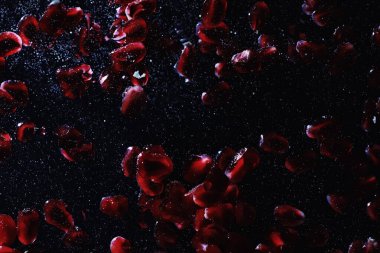 Olgun tatlı nar tohumlarına su damlaları düşer. Metnin için kopyalama alanı olan taze nar arkaplanı. Vejetaryen ve vejetaryen kavramı.